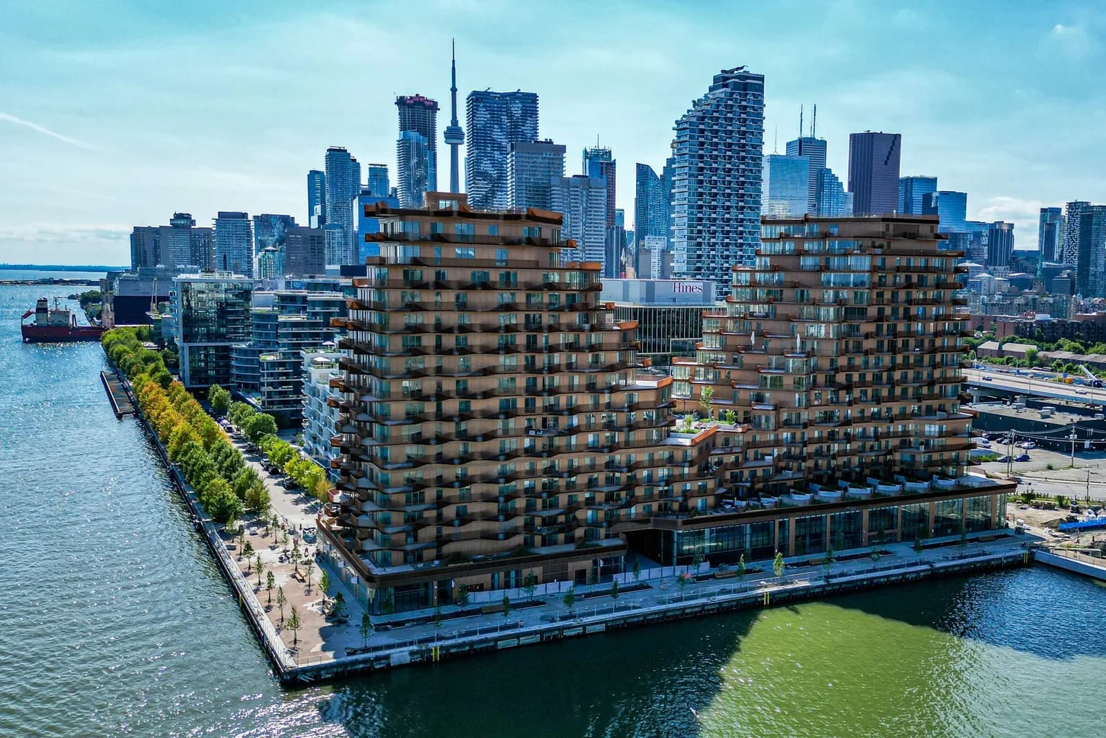 Aerial view of a terraced waterfront condominium in Toronto, with the CN Tower and downtown skyline behind it