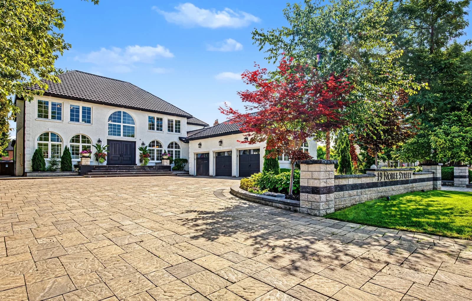 Front exterior of 19 Noble Street in Markham: a white two-storey home with arched windows, a three-car garage and an interlocking stone driveway