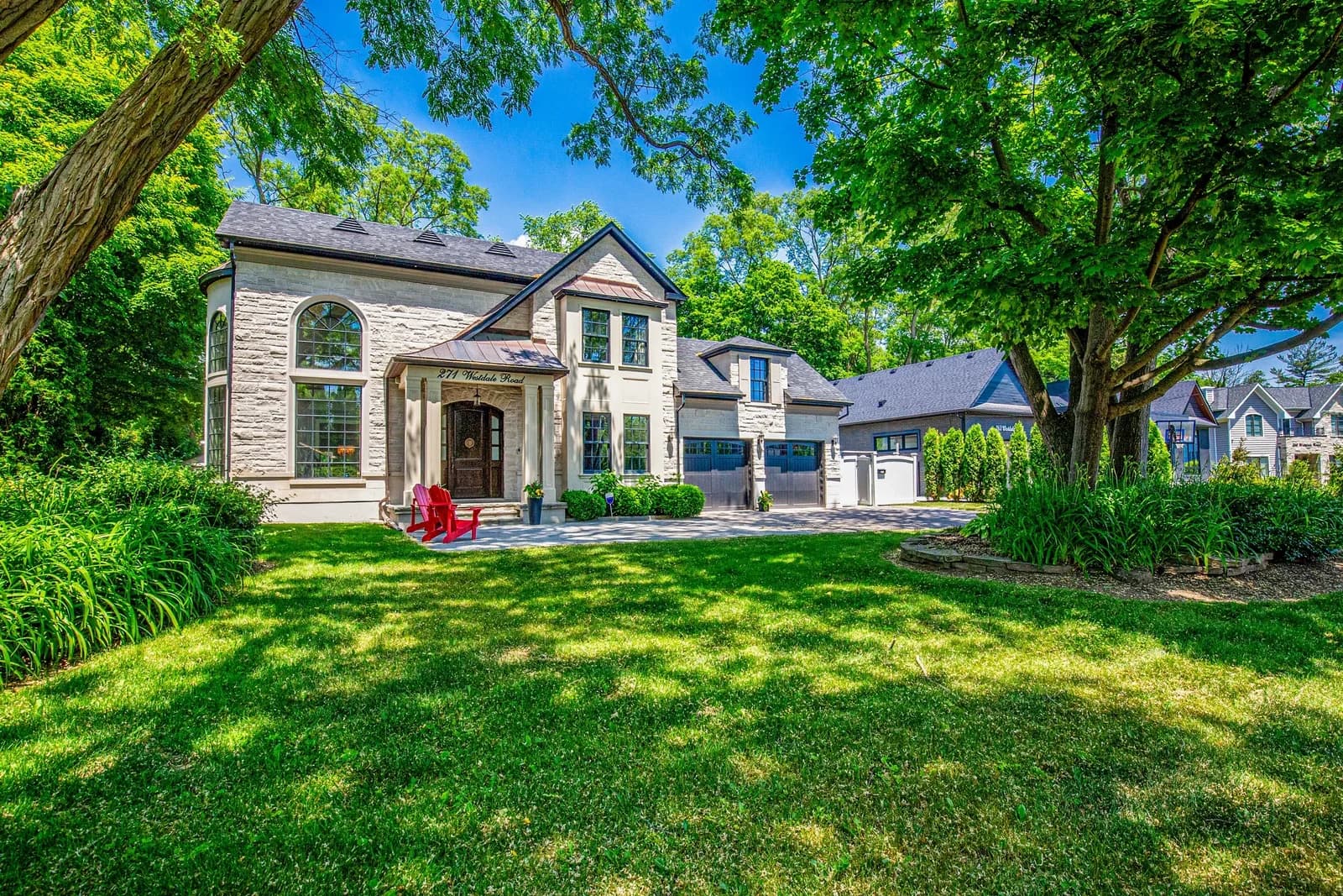 Front exterior of 271 Westdale Road in Oakville, a stone two-storey home with a gabled entry, set behind a wide lawn under mature trees