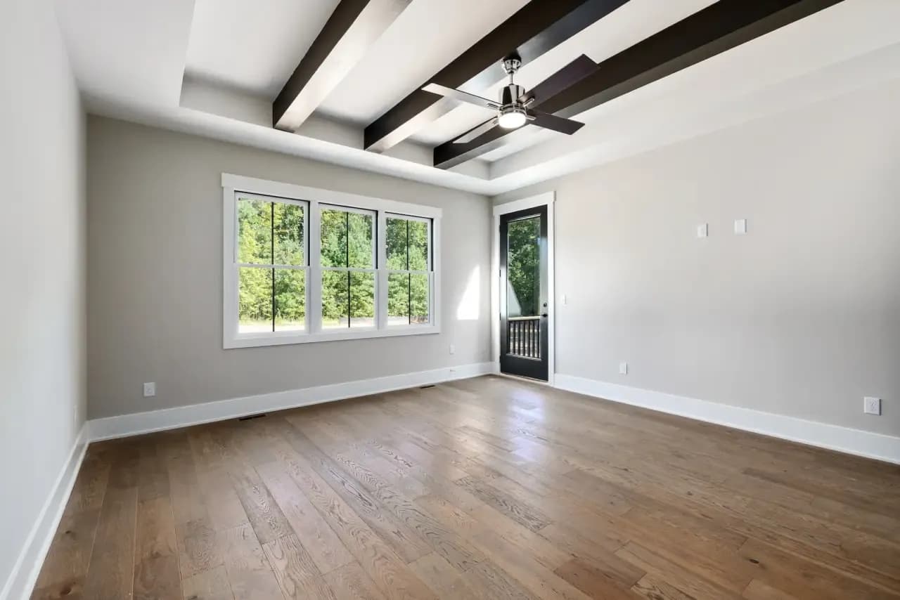 Empty room with exposed ceiling beams and large windows before virtual staging