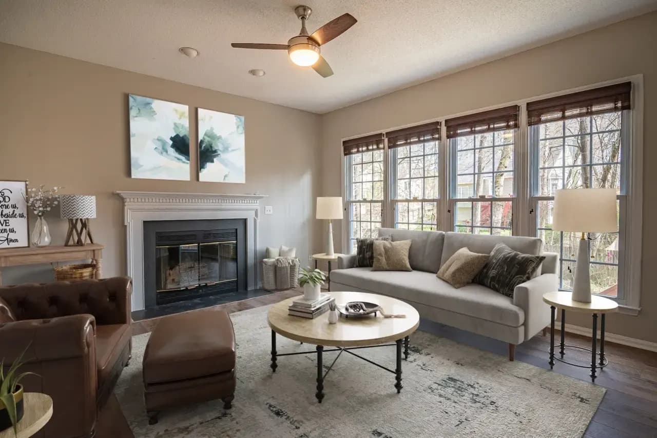 Same fireplace room virtually staged with a sofa, armchair and round coffee table