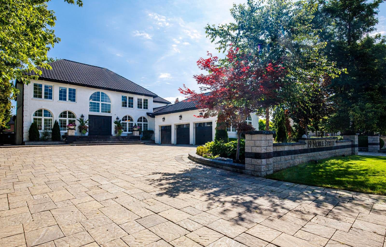 White house and attached garages beside a paved driveway at 19 Noble Street, Markham